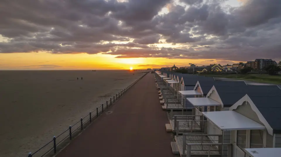 Beach huts along the promenade at St Annes on Sea at sunset, beside the wide sands of the Fylde coast